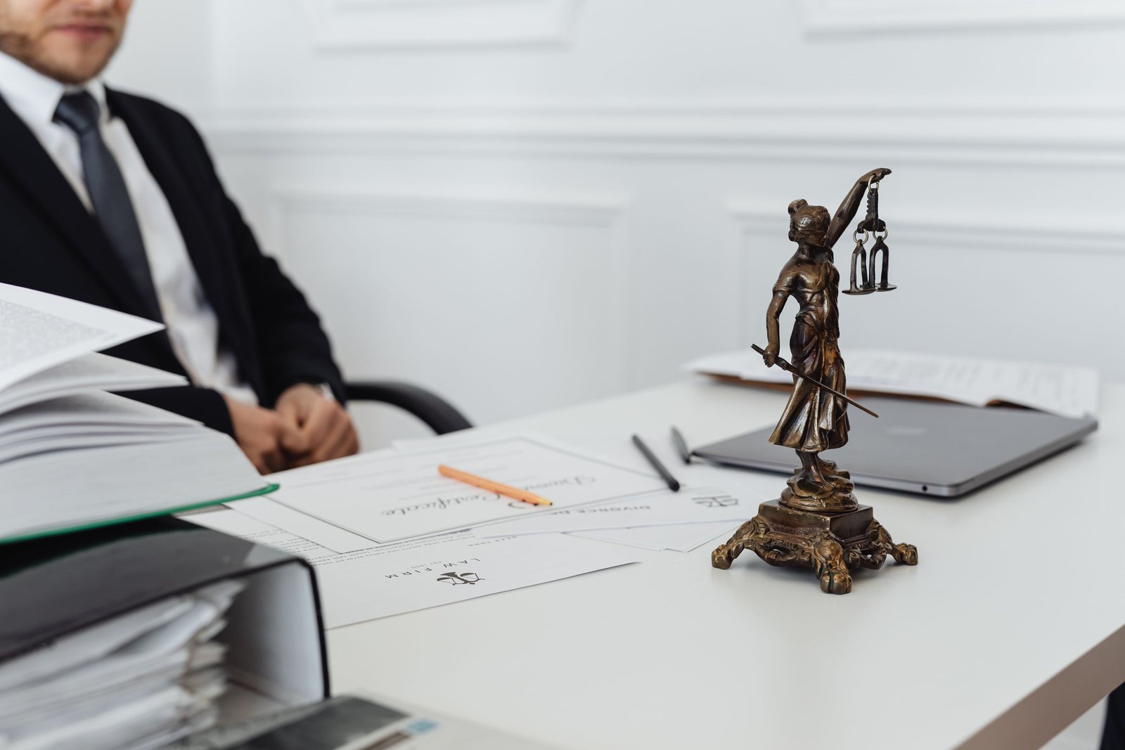 Mesa de trabalho de advogado com estátua da Justiça, documentos e laptop